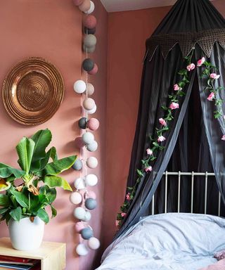 A pink bedroom with rose garland detail, grey nook and pink/grey fairy lights