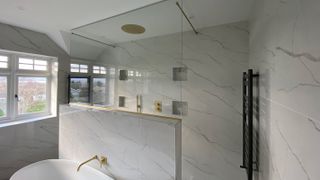 marble bathroom with dividing wall between shower and bath