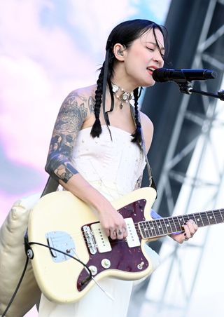 michelle zauner of japanese breakfast performing live at a festival wearing a white dress on stage