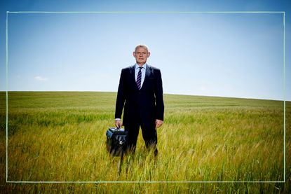 Doc Martin holding his briefcase standing in a field under a blue sky