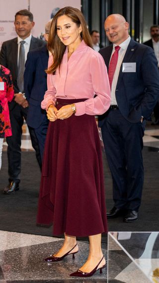 Queen Mary of Denmark wearing pink skirt with burgundy skirt and kitten heels