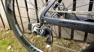 The rear end of a black carbon bicycle, with wireless derailleur and a spotless chain and cassette