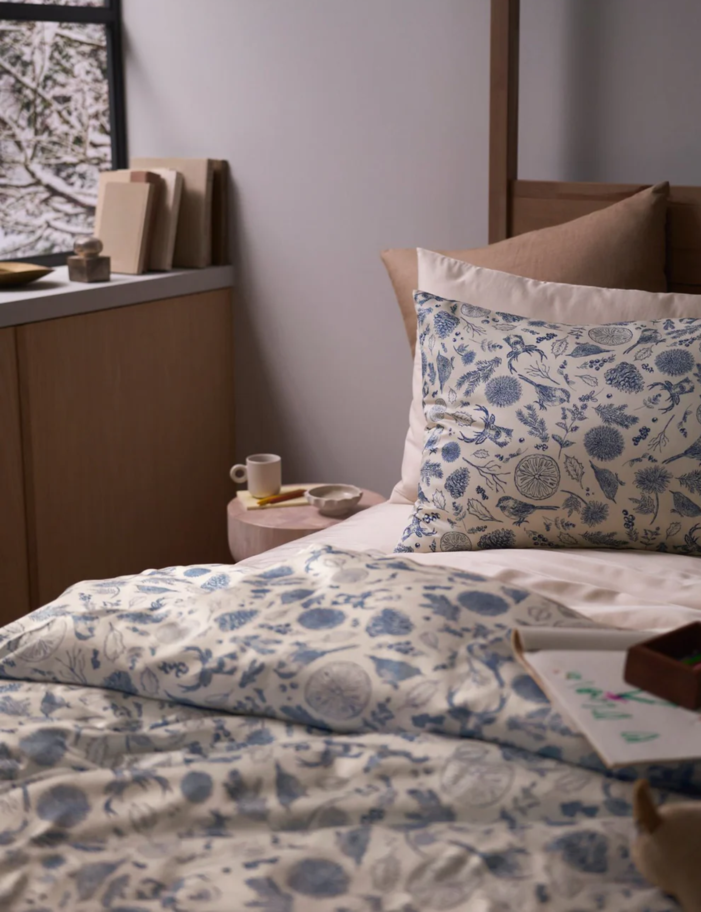 Cozy Earth winter toile bedding styled in a dimly lit bedroom with cozy, ecclectic accents