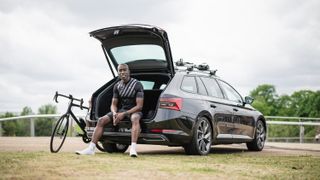 A black man sits in the boot of a ŠKODA in cycling kit