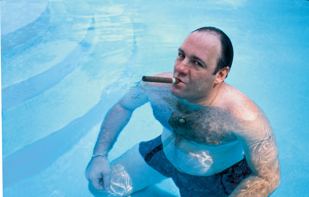 American actor James Gandolfini, as Tony Soprano, smokes a cigar while he stands in pool, in publicity still for the HBO cable TV series 'The Sopranos,' 1999