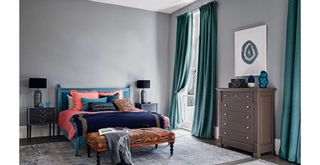 gray bedroom with high ceilings with rich blue curtains hung to the floor to show how to make a bedroom look expensive