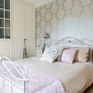 bedroom with wallpaper on wall and pillows on bed
