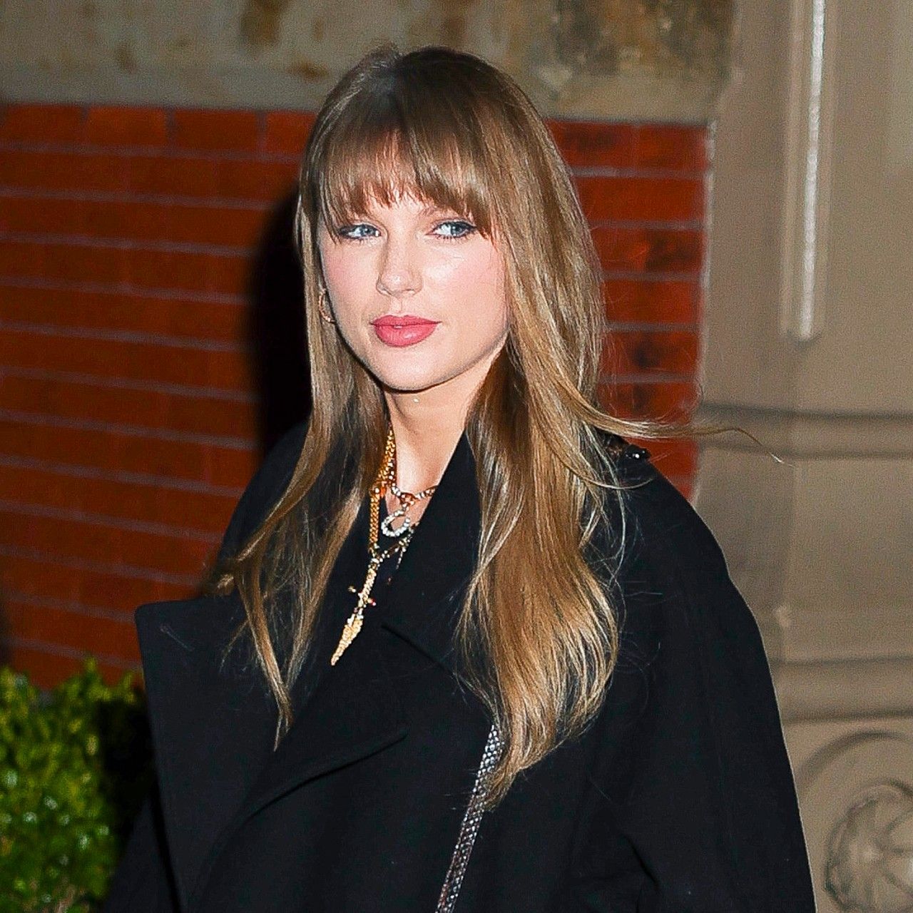 a white woman with dark blonde hair walking in a black trench coat