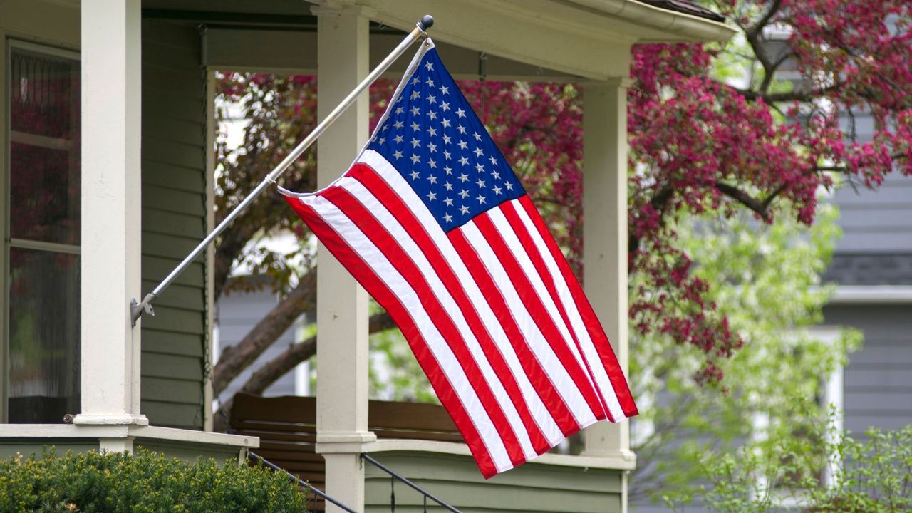 A USA flag hanging from a pole on a porch