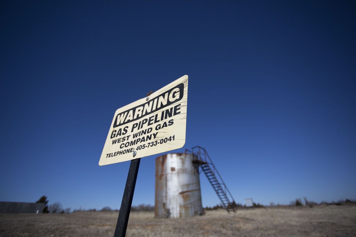 Wastewater injection related to oil and gas drilling can trigger earthquakes in Oklahoma. Here, a sign showing a gas line in front of a storage tank in McLoud, Oklahoma.