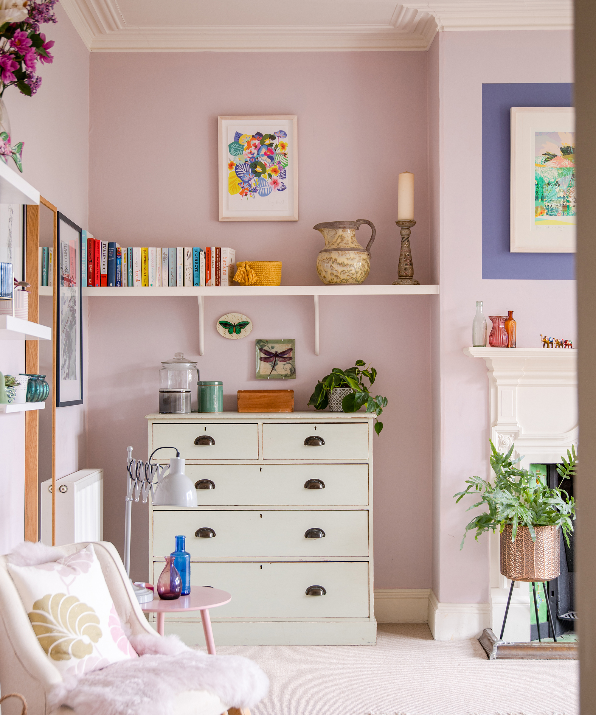 lilac painted bedroom with vintage chest of drawers, wall shelf and fireplace