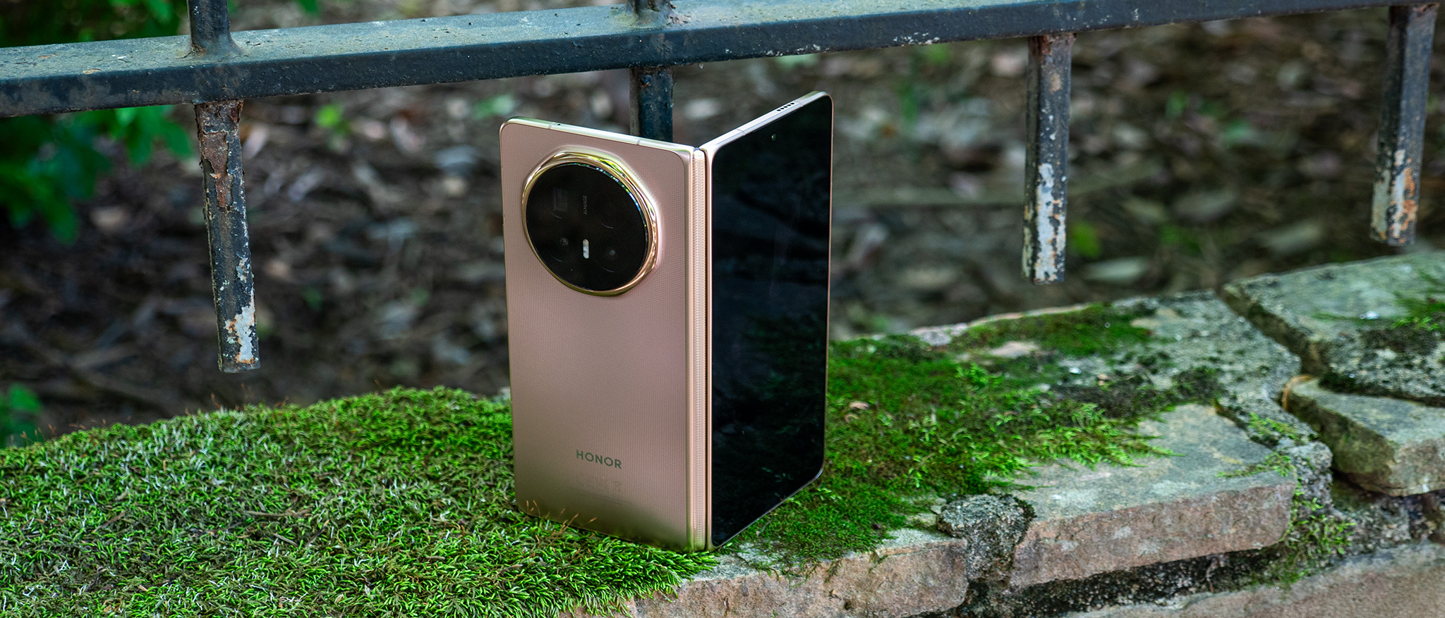 The gold Honor Magic V6 on a moss-covered stone wall
