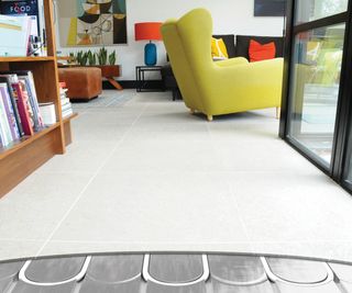 living room with arc cut in tiled floor showing underfloor heating pipes below