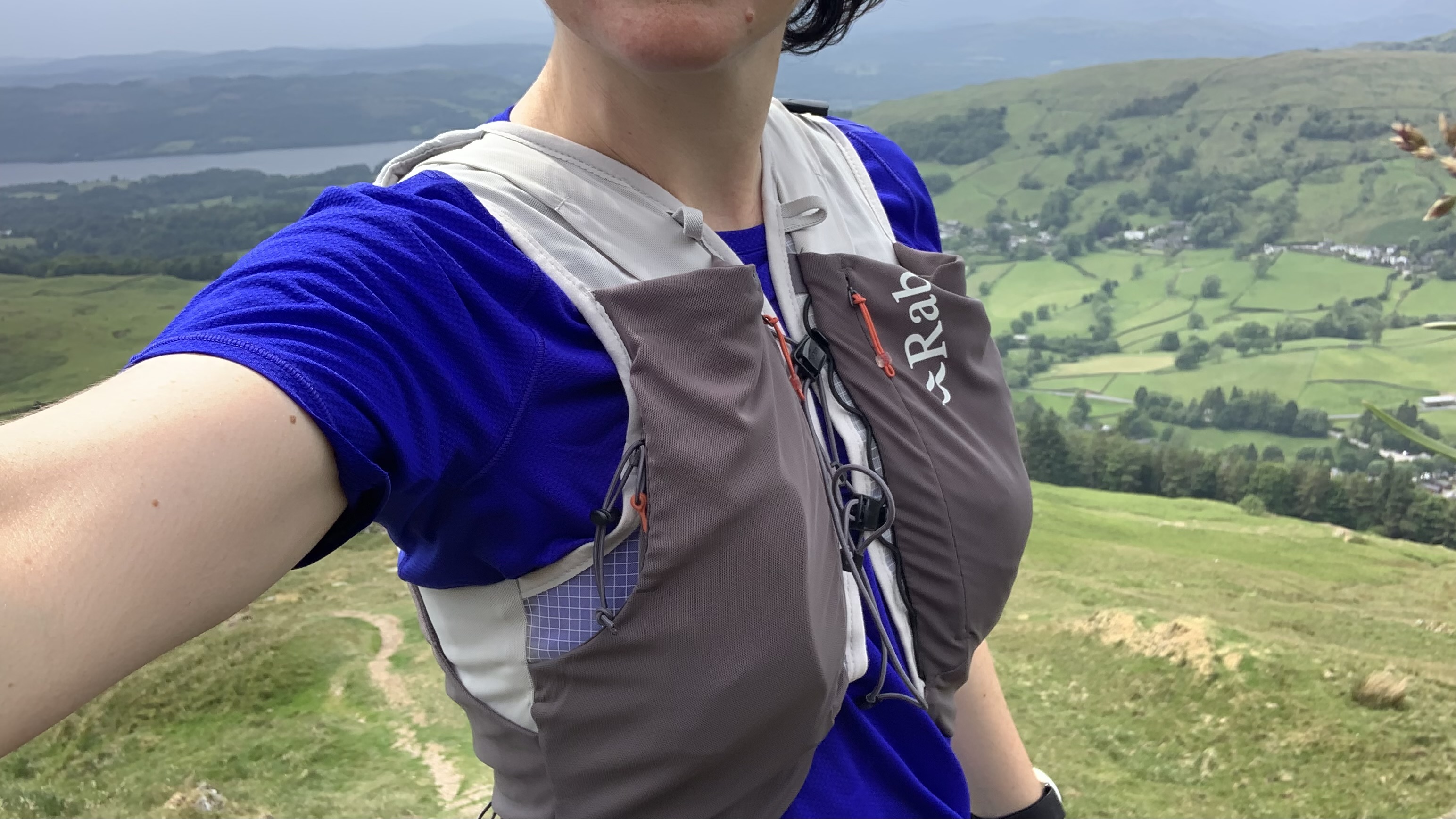 Female runner wearing the Rab Veil 12L Lightweight Running Vest with hills in the background