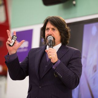 man with black blazer holding microphone