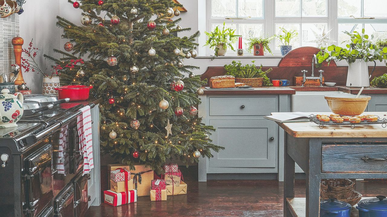 A kitchen decorated for Christmas with a large tree in the corner