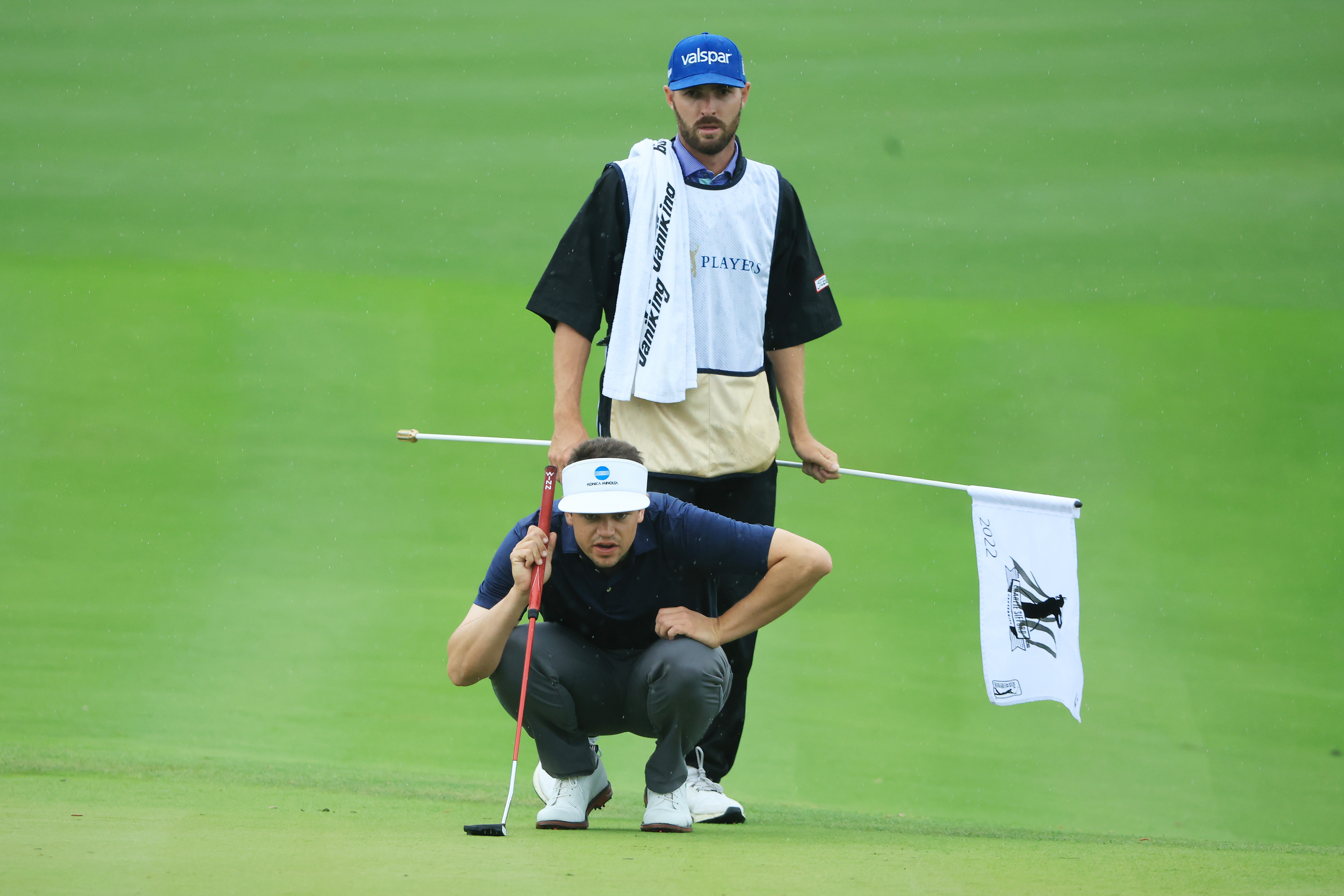 Dave Pelekoudas stands behind Beau Hossler who is lining up a putt at the 2022 Players Championship