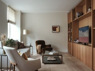 neutral living room with brown chair grey sofa and wood storage