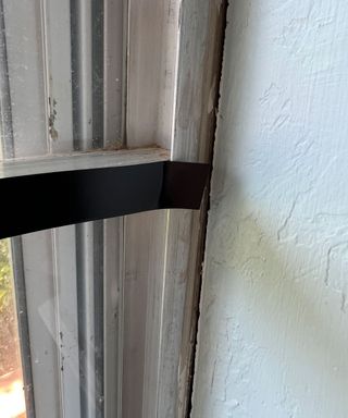 Dori Turner upgrading basic white window frames with black electrical tape to create Critall-style window frames on a budet