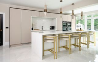 large kitchen with pink cabinets, long kitchen island with seating and lighting above