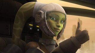 Hera Syndulla is a green-skinned Twi'lek with two head tails (known as lekku) protruding from the top left and right of her head. She is sitting in the cockpit of a spaceship, giving us a thumbs up. She is wearing a white helmet with a clear visor and a brown jacket and brown gloves.