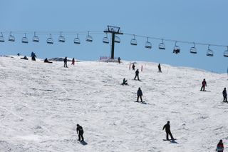 Skiers at Hotham Resort in Australia go down a slope with lifts in the background