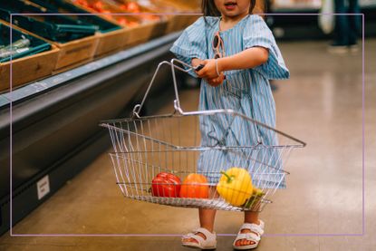 Young girl carrying basket with fruit in