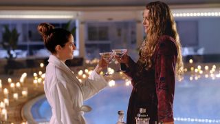 Anna Kendrick and Blake Lively having martinis near a pool with a ton of lit candles in Another Simple Favor