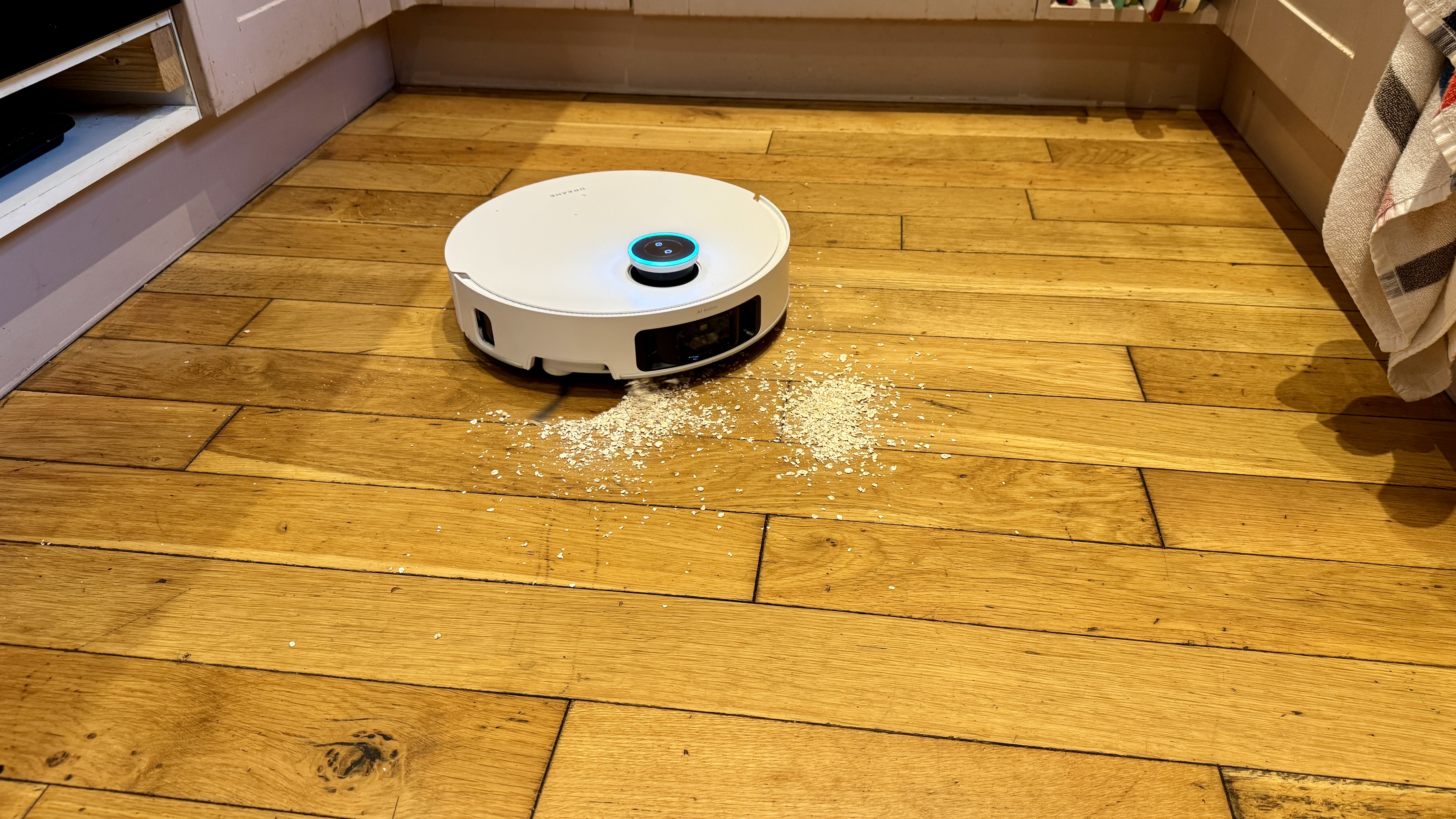 Dreame Matrix10 Ultra robot vacuum clearing oats from a wooden floor