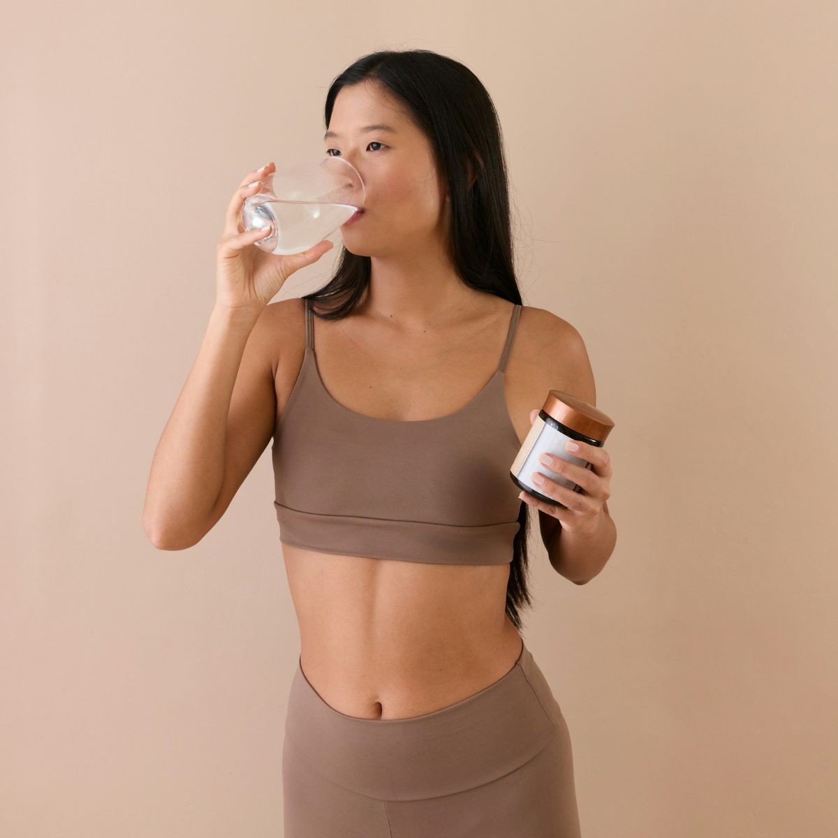 woman drinking supplement in gym gear