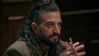 Mark Ballas holding his hands at the Round Table on The Traitors. 