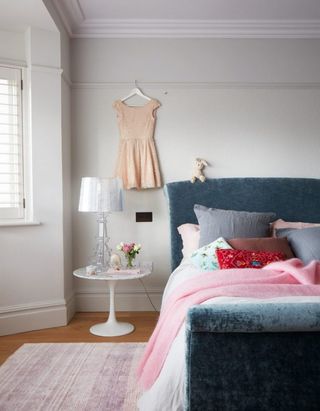 Blue velvet bed in pale grey bedroom with pink bedding