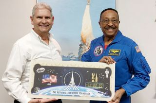 Astronaut Winston Scott (at right) and Bob Mellor, strategic numismatic advisor for the Astronauts Memorial Foundation, hold an oversized print of the Artemis I collectible note.
