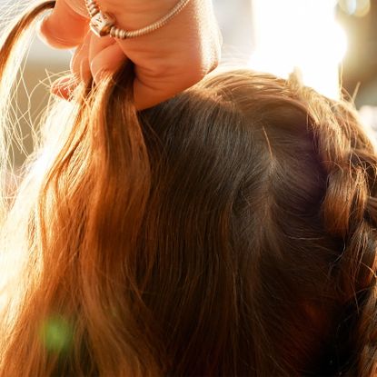 cropped hands of female hairstylist styling girl hair
