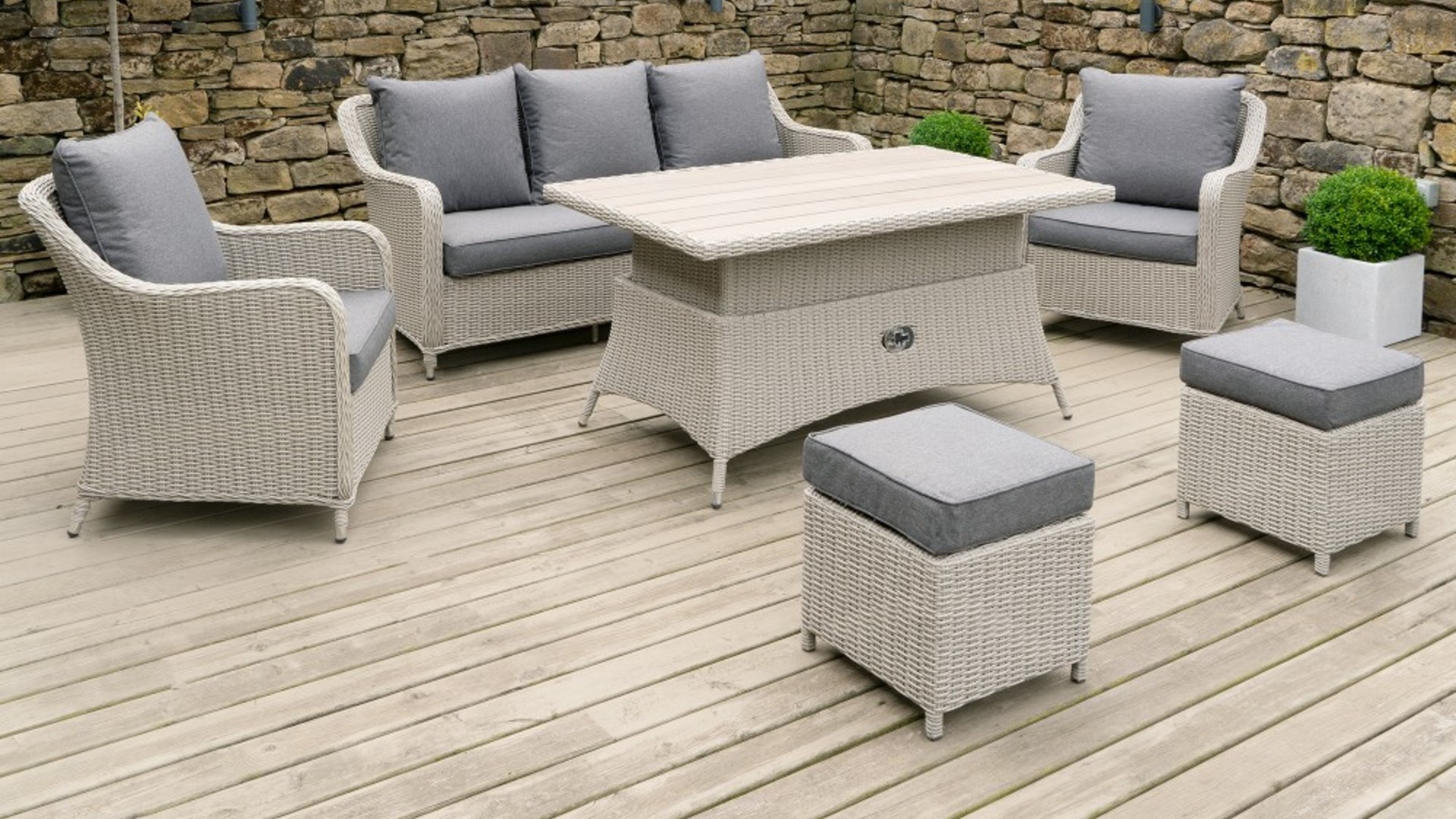 A rattan garden sofa and chairs with riser table on outdoor decking