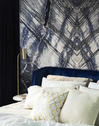 blue and white bedroom with blue marble backdrop, blue velvet bed, white bedding, gold table lamp