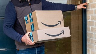 A delivery person rings a doorbell holding Amazon packages