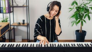 Woman playing on a digital piano with headphones on