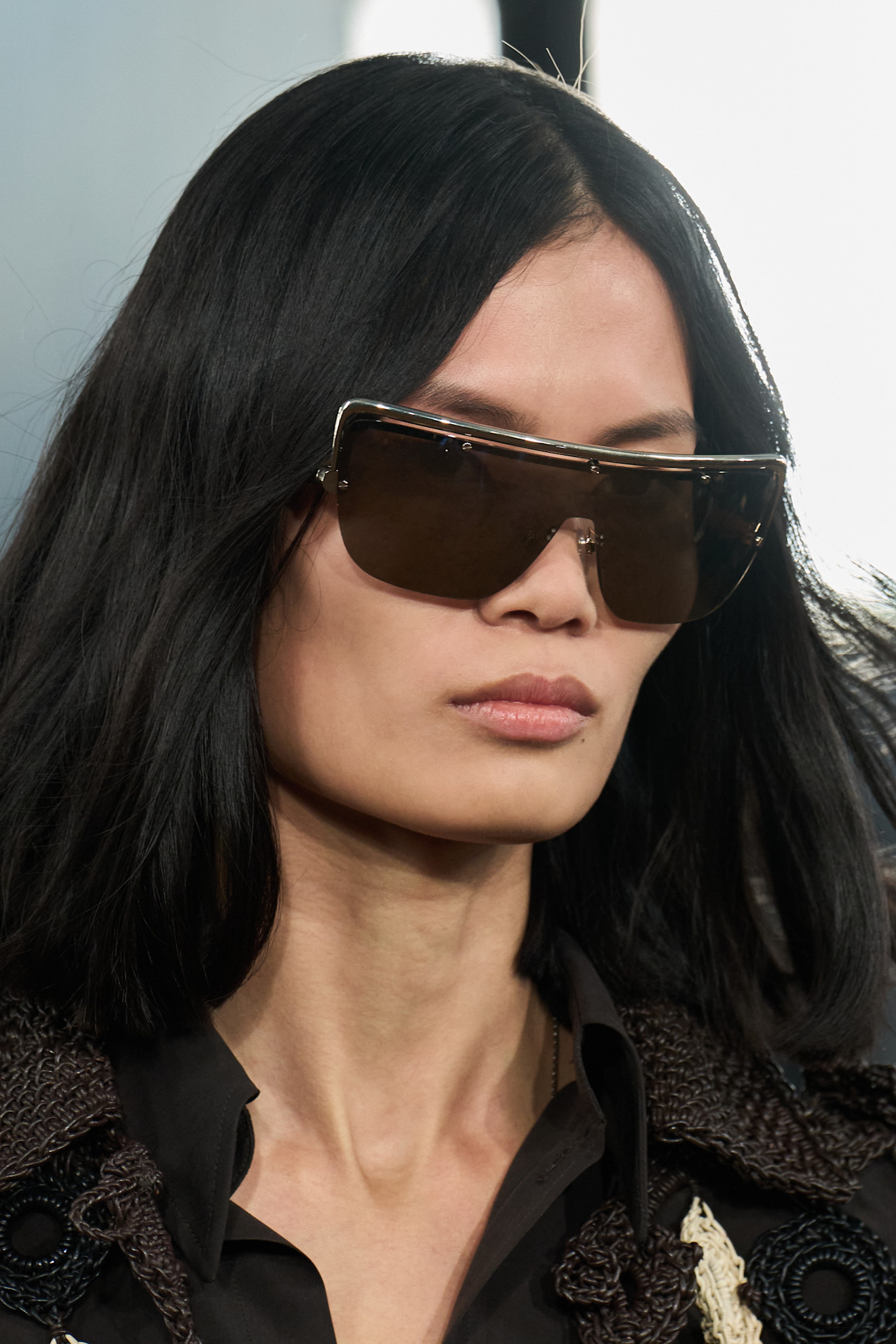 A model at Burberry SS26 show with loose waves and natural makeup wearing dark sunglasses