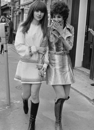 Fashion models Chrissie Shrimpton, left, and Linda Keith walk along a street in Soho wearing miniskirts followed by photographers, London, April 17th 1967