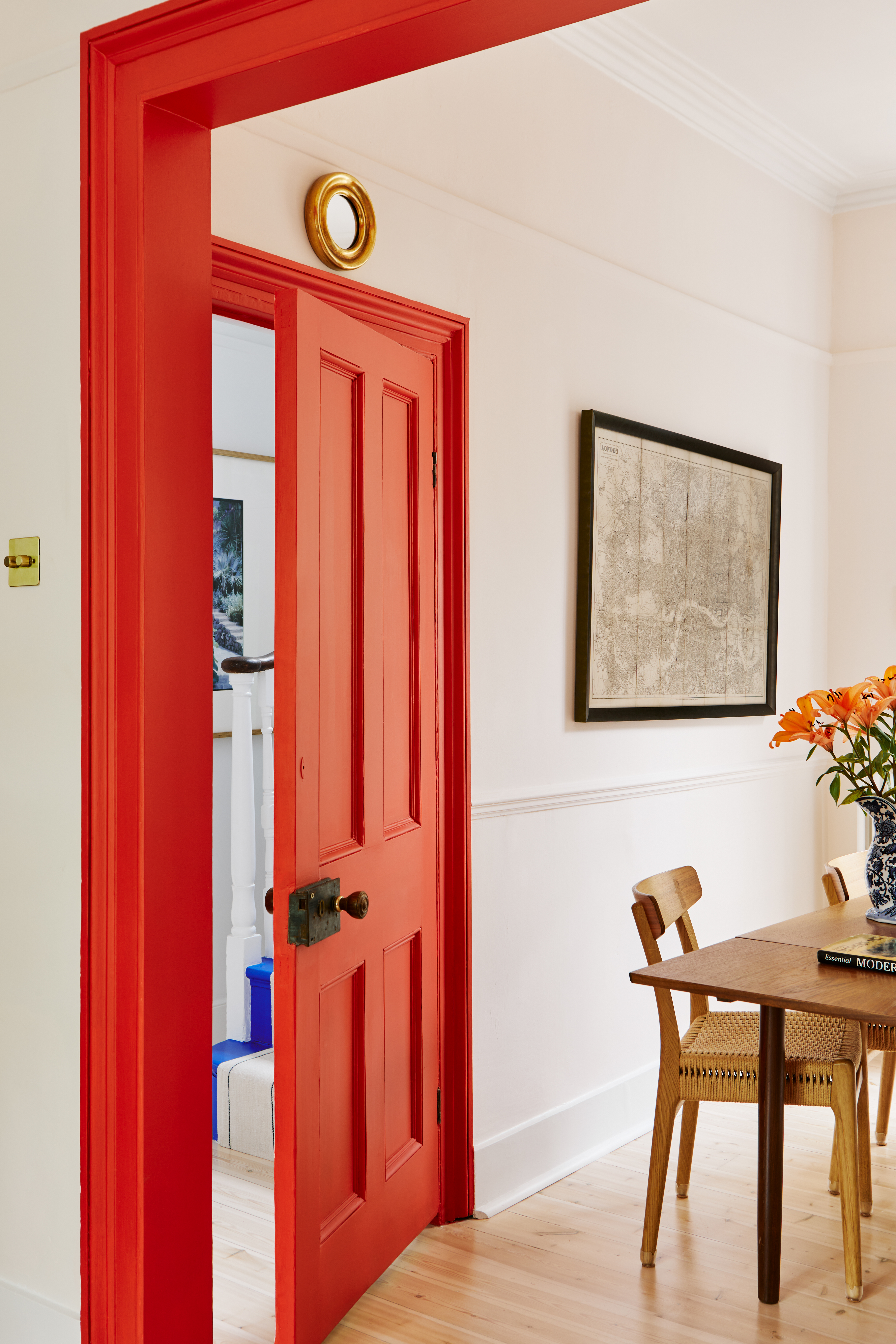 Door surrounds painted tomato red in a contemporary white dining room