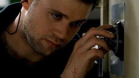 Leo Woodall turning the combination lock on a safe and focusing intently