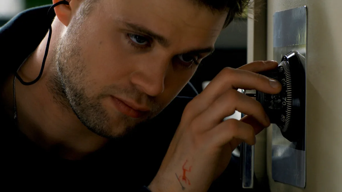 Leo Woodall turning the combination lock on a safe and focusing intently
