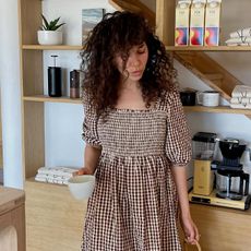 Woman in coffee shop wears brown gingham dress