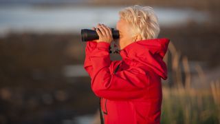 Best binoculars: Image shows mature woman using binoculars outdoors