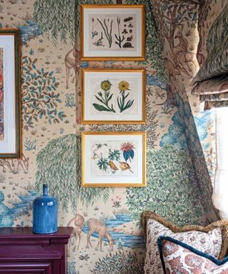 A room with bright green patterned wallpaper and three pieces of art hung in a vertical stack