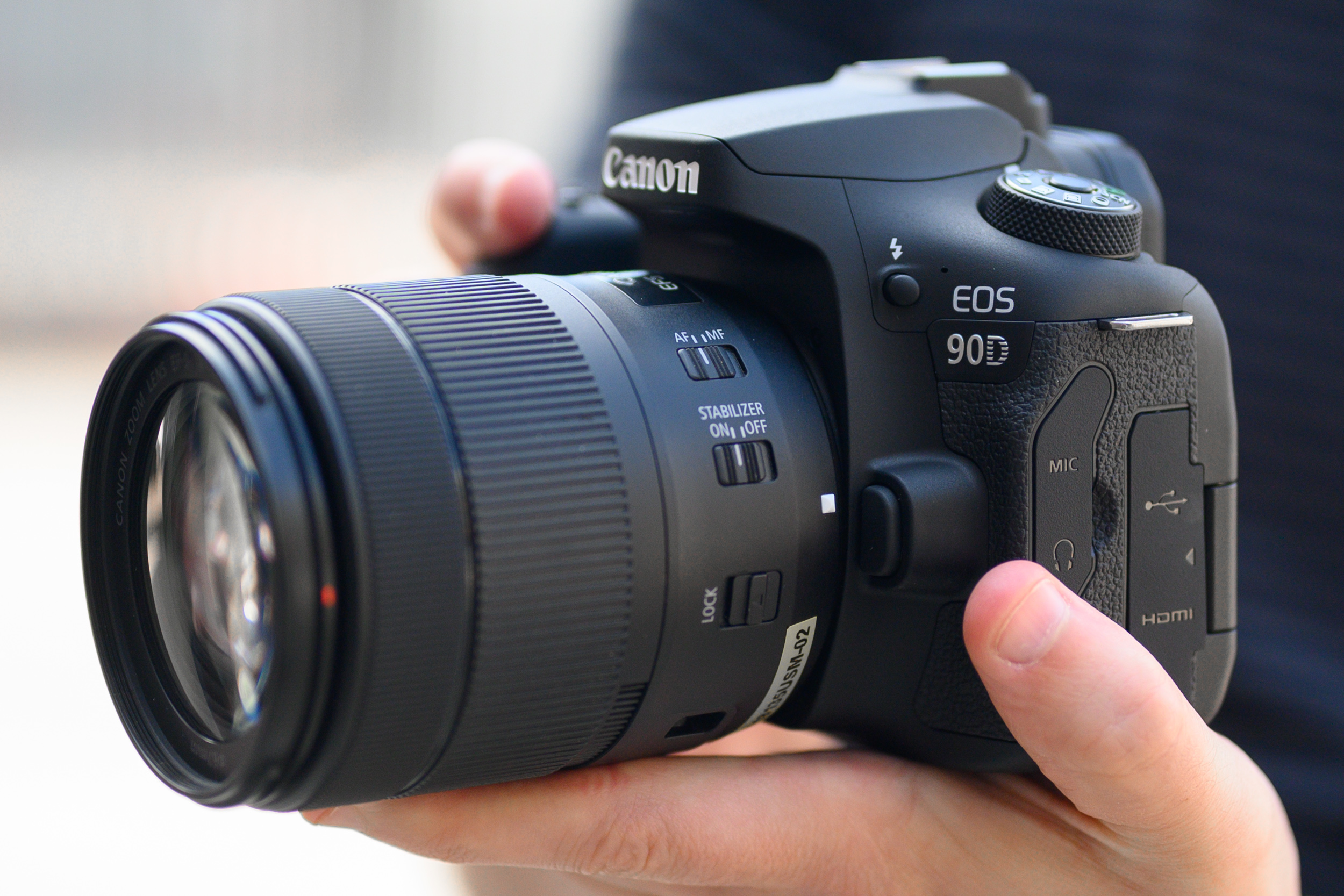 A hand holding the Canon EOS 90D camera