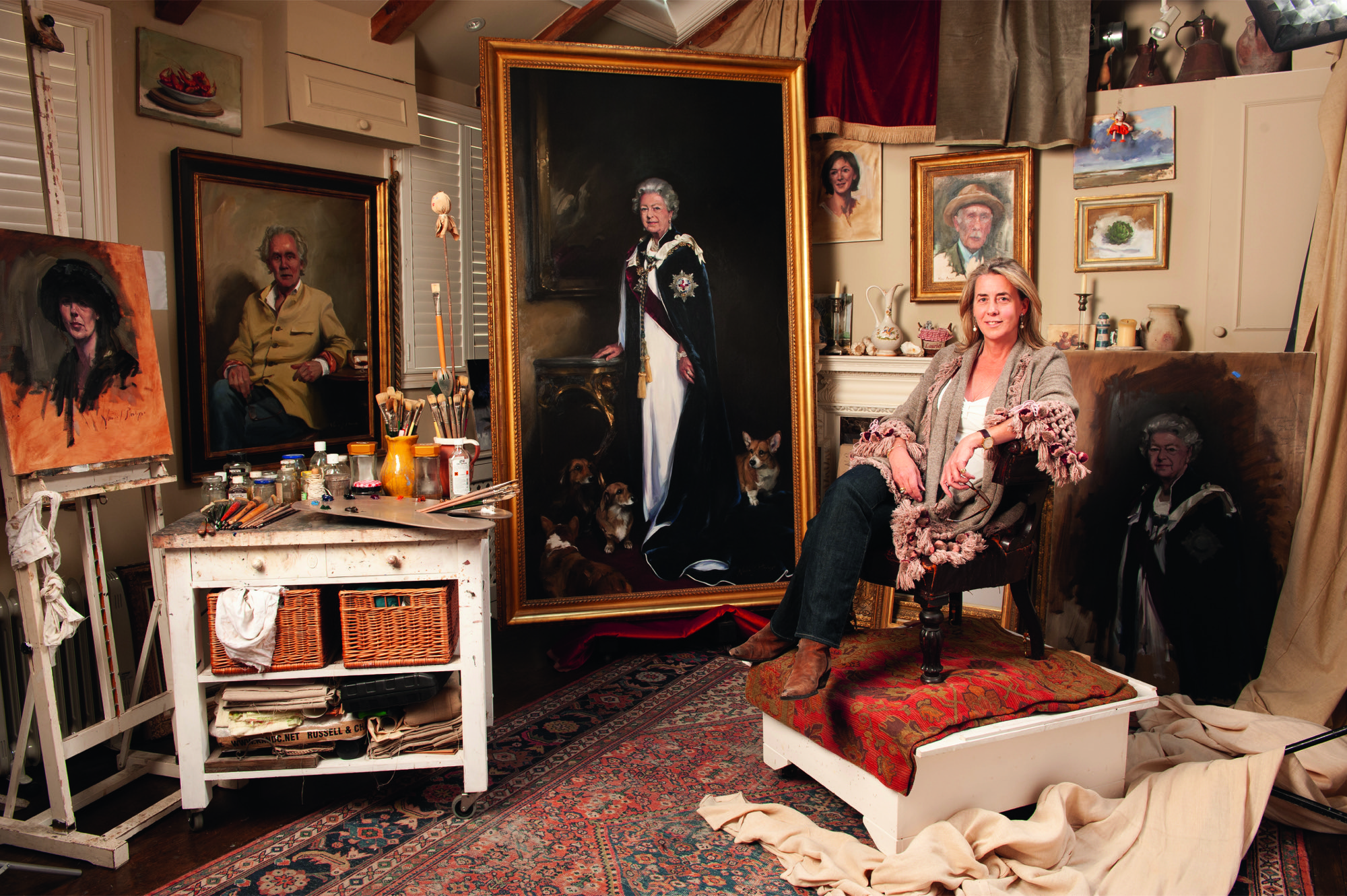 Nicky Philipps in her studio surrounded by paintings, one of which is of Elizabeth II