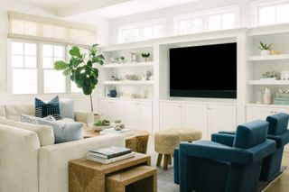 A neutral living room with white walls, cream sofas and blue seating