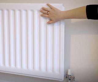 Woman's hand on white radiator